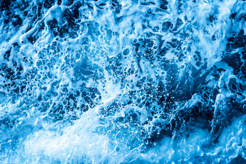 Aerial Ocean water surface with foam and waves behind of fast moving powerful engines.
