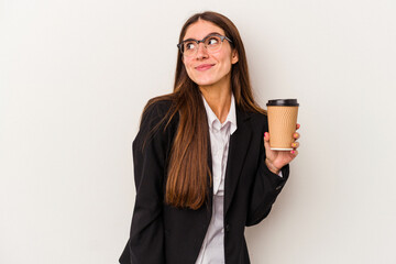 Young caucasian business woman holding a takeaway coffee isolated on white background dreaming of...