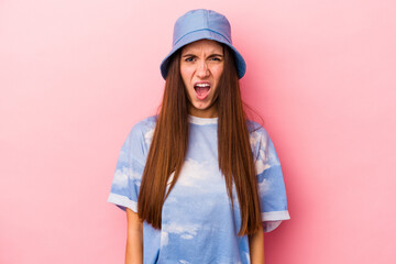 Young caucasian woman isolated on pink background screaming very angry and aggressive.