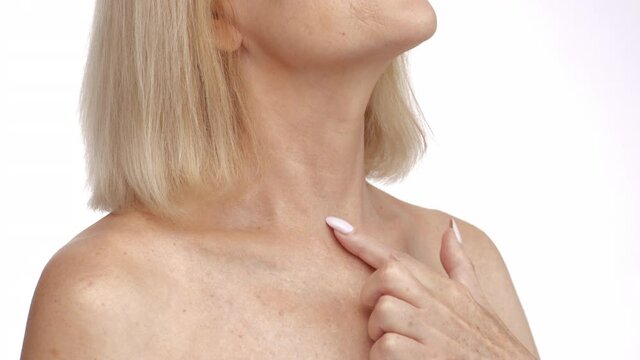 Anti aging body care. Close up shot of unrecognizable senior woman stroking her neck and neckline, enjoying smooth skin