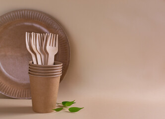 Set of Wooden forks in a paper cup with a green sprig on a cream background. Eco friendly stuff concept. Horizontal orientation. Copy space.