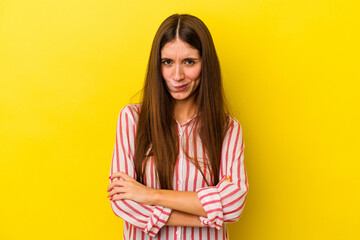 Young caucasian woman isolated on yellow background frowning face in displeasure, keeps arms folded.