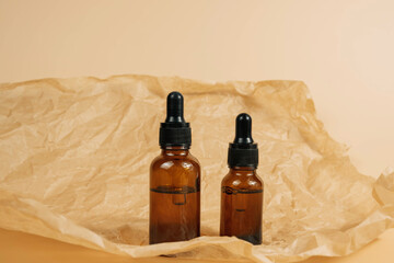 Mock-up of a set of empty cosmetic containers with pipettes made of amber glass on a beige...