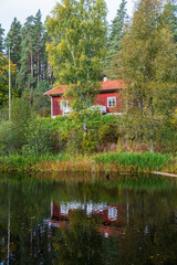 Obraz premium Red cottage by a forest lake