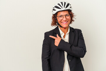 Middle age latin business woman wearing a bike helmet isolated on white background smiling and pointing aside, showing something at blank space.