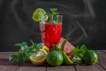 Watermelon mojito in a transparent glass, fruits and mint, on a dark background