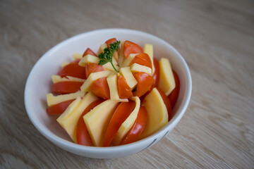 dish decorated with tomato, cheese and parsley in a wooden background