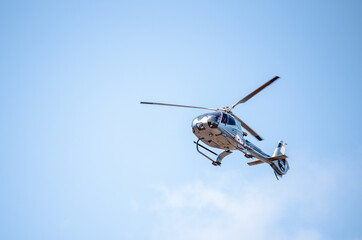 Flying helicopter in blue sunny sky