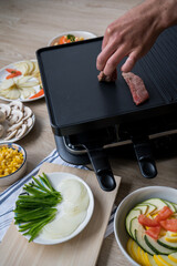man putting meat  on the raclette