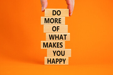 Do what makes you happy symbol. Wooden blocks with words 'Do more of what makes you happy'. Businessman hand. Beautiful orange background, copy space. Business, do what makes you happy concept.