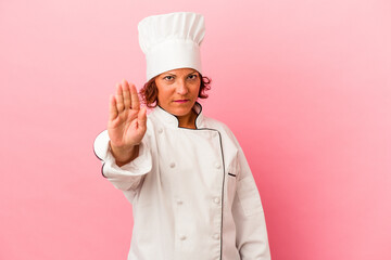 Middle age latin woman isolated on pink background standing with outstretched hand showing stop...