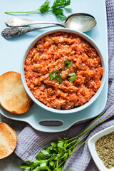 Eggplant caviar in blue bowl and fresh vegetables on background