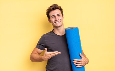 smiling cheerfully, feeling happy and showing a concept in copy space with palm of hand. yoga mat concept