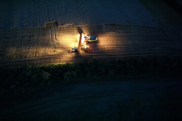 combine harvestor on field during night shift aerial drone view 