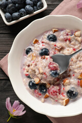 Tasty oatmeal porridge with toppings on wooden table, flat lay