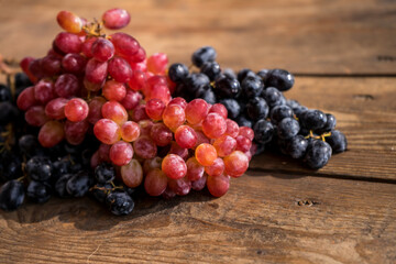 Grapes on a wooden table. Fresh branch of red grapes with leaves