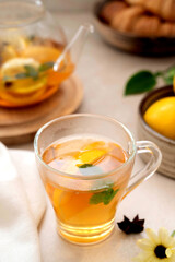 Tea in glass cup with lemon, mint and honey. Delicious fruit, herbal teapot and cup.