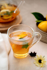 Delicious fruit tea with mint, herbs, lemons and orange slices. Glass teacup and glass cup of tea.