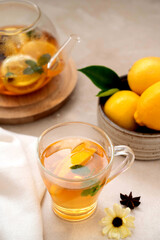 Tea in glass cup with lemon, mint and honey. Delicious fruit, herbal teapot and cup.