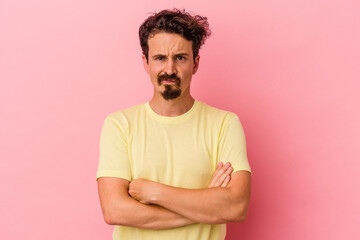 Obraz premium Young caucasian man isolated on pink background frowning face in displeasure, keeps arms folded.