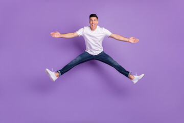 Full size photo of young man happy positive smile active energetic jump split isolated over violet color background