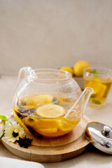 Glass tea pot with fruit delicious herbal tea on bright background.