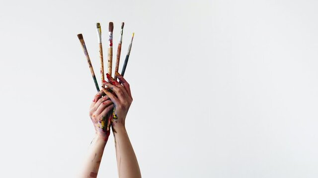 Art painting. Drawing course. Artist education. Creative lifestyle. Woman painter hands holding set of messy oil paint colorful kit of paintbrushes isolated on white copy space.