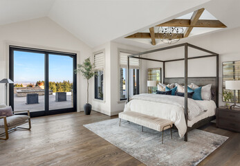 Bedroom in new luxury home with hardwood floors, sliding glass door leading to patio, and skylights with wood cross beams and elegant pendant light - obrazy, fototapety, plakaty