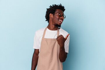 Young african american store clerk isolated on blue background points with thumb finger away,...