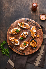Chanterelle sandwiches with cheese. Open faced sandwich with creamy cheese, seasonings and pepper and fresh parsley on an old wooden background. Mock up. Top view.