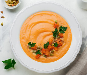 Homemade pumpkin soup in white ceramic dish on an old concrete or stone background. Selective focus. Top view. Copy space