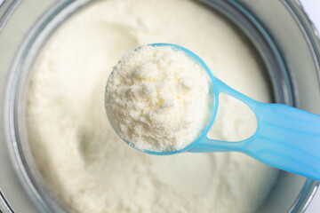 Scoop of powdered infant formula over can, top view. Baby milk