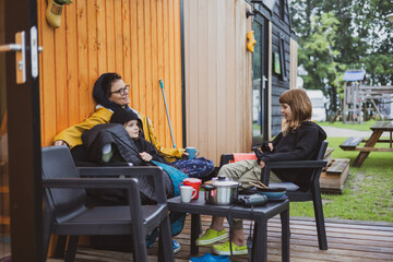 Mother and children talking in front of the wooden cabin at the campsite 
