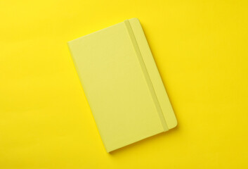New stylish planner with hard cover on yellow background, top view