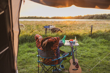 Woman relaxing in front of the tent during sunset 
