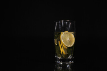 Drink in a glass with mint and lemon on a black background
