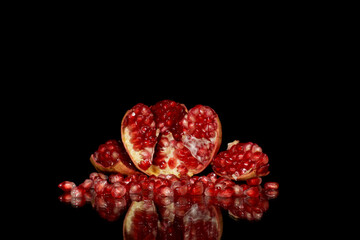 Ready-to-eat pomegranate on a black background, reflection in the glass