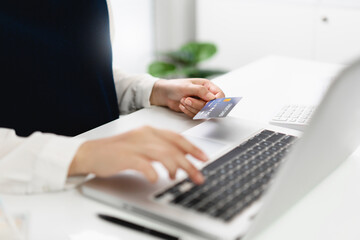 Woman spending money on Online shopping. Hands holding credit card and using laptop working at home e-commerce and internet banking concept