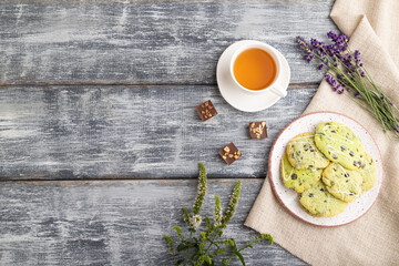 Green cookies with chocolate and mint with cup of green tea on gray wooden background. top view, copy space.