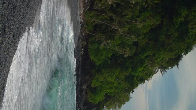 Vertical Video. Waves crashing onto a deserted tropical island beach.