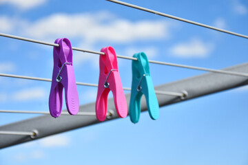 A close up image of brightly colored clothes pins hanging on a clothes line. 