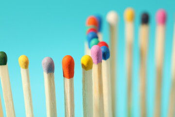Matches with colorful heads on light blue background, closeup