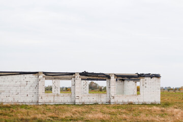 Defocus close-up white private unfinished brick house on a construction site on the autumn meadow village. Unfinished house from a white brick. Construction of private houses. Out of focus