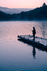 Lone fisherman on a pier before sunrise