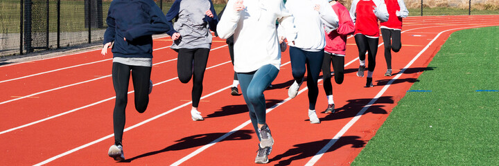 High school girls run training on a track together