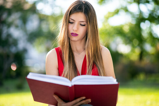 Young woman sitting in a park and reading a book