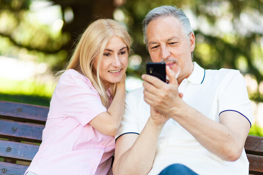 Adult couple using a smartphone together at the park