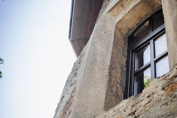 The wall of an old building made of red brick and stone. Window in the tower of an ancient castle