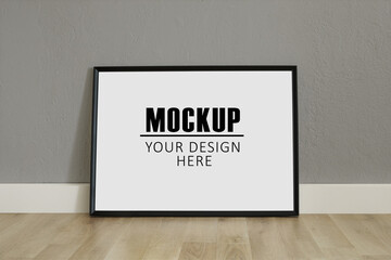 Frame, poster mock up with horizontal black frame. Empty frame standing on the wooden floor, grey...