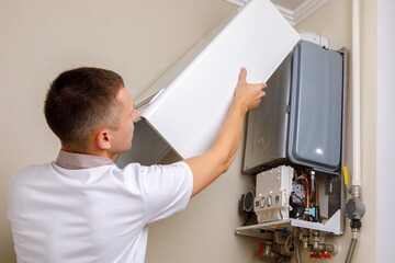 Plumber attaches Trying To Fix the Problem with the Residential Heating Equipment. Repair of a gas...